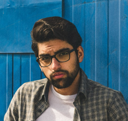 Man with glasses against a blue wooden wall